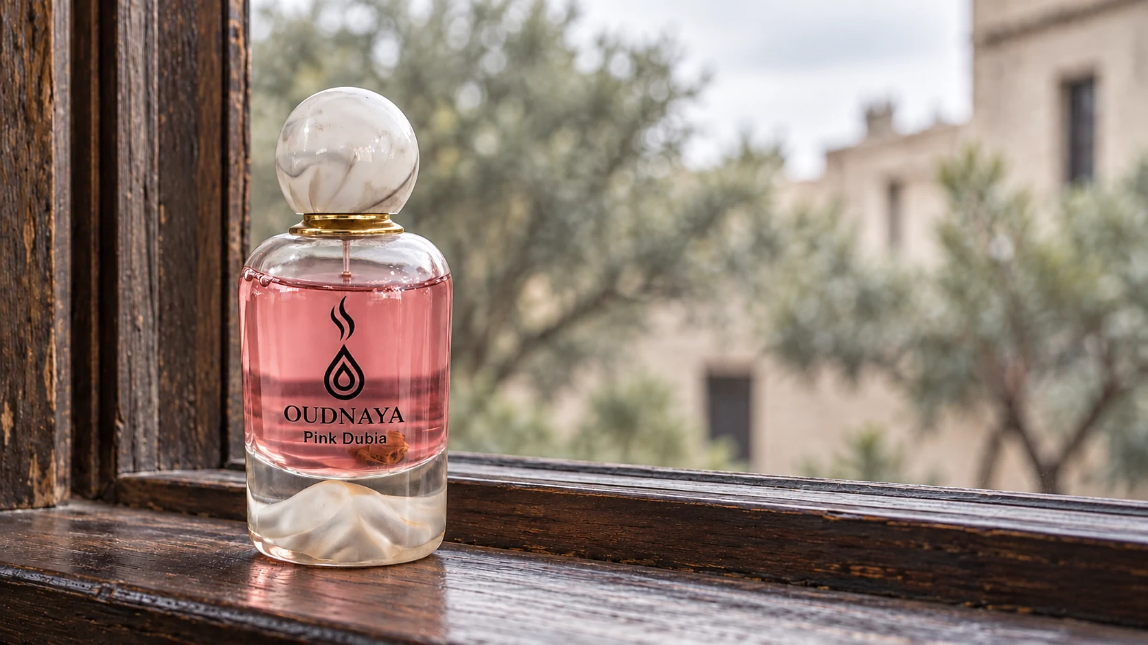 Frasco OUDNAYA Pink Dubai junto a una ventana